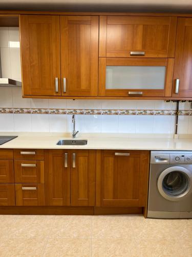 a kitchen with wooden cabinets and a washing machine at Pinares de Boo in Boó de Piélagos