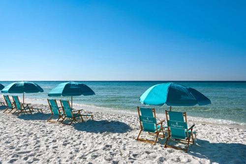 a group of lawn chairs and umbrellas on a beach at Edgewater #303 in Destin