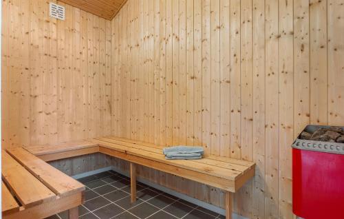 a wooden sauna with a bench and a red trash can at Beach Front Home In Hjørring With Sauna in Hjørring