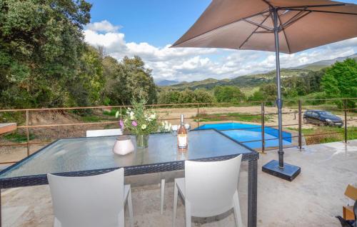 un tavolo con sedie e un ombrellone in un patio di Cozy Home In Petreto-Bicchisano a Petreto-Bicchisano