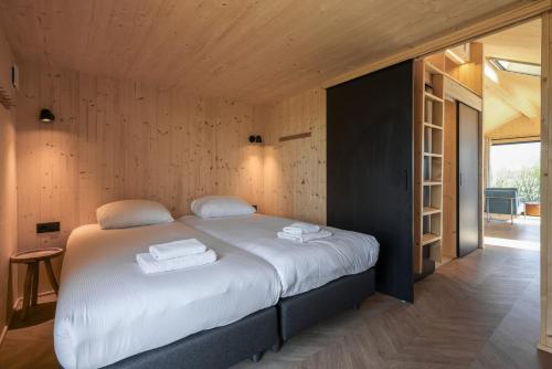 een slaapkamer met een groot bed en handdoeken bij Hello Zeeland - Tiny House Zeeuwse Liefde 2 in Westkapelle