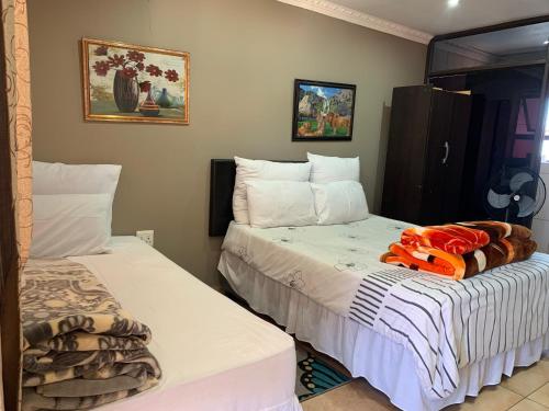 dwa łóżka siedzące obok siebie w pokoju w obiekcie M & J HOTELS w mieście Johannesburg