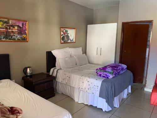 ein Schlafzimmer mit einem Bett mit einer lila Decke darauf in der Unterkunft M & J HOTELS in Johannesburg