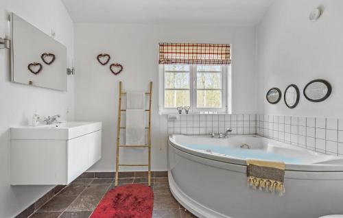 uma casa de banho branca com uma banheira e um lavatório em Nice Home In Sby With Kitchen em Sæby