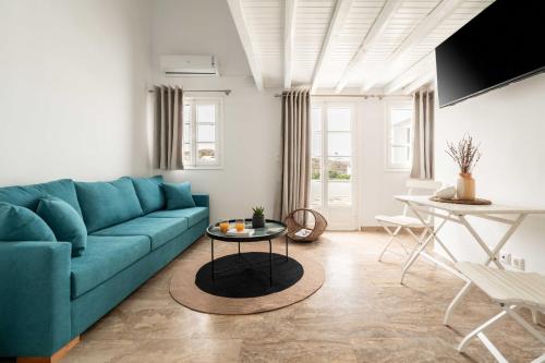 a living room with a blue couch and a table at Tagoo Studios Mykonos in Mýkonos City