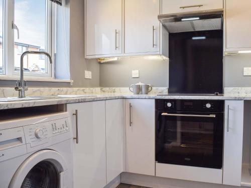 uma cozinha com armários brancos e um aparelho preto em Racing Retreat em Towcester