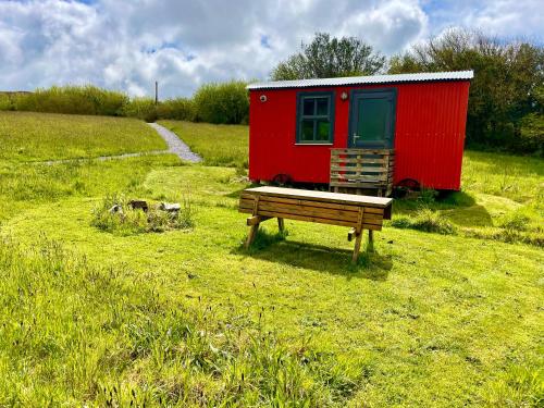 a red trailer sitting in a field with a bench at Stepping Stones Glamping little red in Bantry