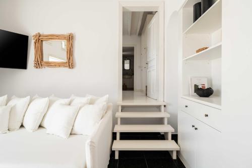 a bedroom with white walls and a bed with white pillows at Tagoo Studios Mykonos in Mýkonos City