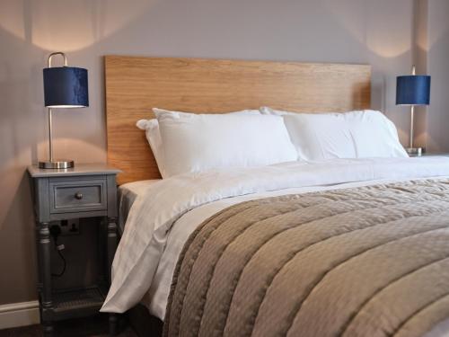 a bedroom with a bed and a nightstand with two lamps at 1885 the Venue - Pub, Restaurant, Rooms & Function House in Halifax
