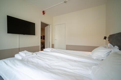 a white bed with white pillows and a flat screen tv at Solna Park & Hotel in Solna