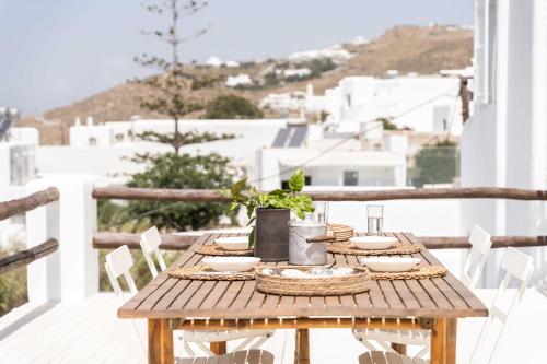 a wooden table on a balcony with a view of buildings at Tagoo Studios Mykonos in Mýkonos City