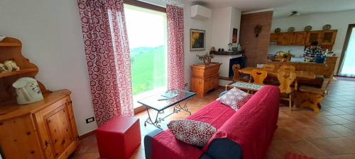 a living room with a red couch and a large window at Casa rustica con vista meravigliosa in Offida