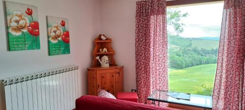 a living room with a red couch and a window at Casa rustica con vista meravigliosa in Offida