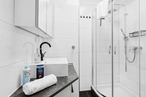 a white bathroom with a sink and a shower at Flexi Home - Balkon , Seeblick & Speed Wlan in Langscheid