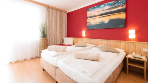 2 Betten in einem Zimmer mit roter Wand in der Unterkunft Gasthof Menüwirt in Sankt Kanzian am Klopeiner See