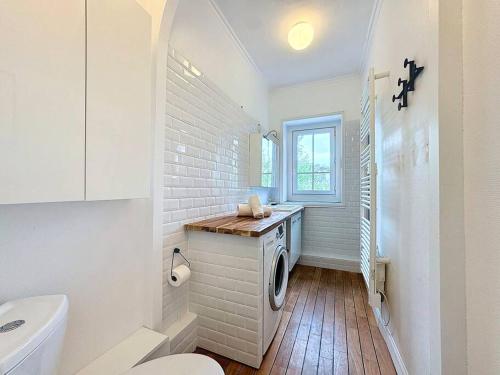 une salle de bain blanche avec une machine à laver à l'intérieur dans l'établissement Le Quai West YourHostHelper, à Deauville