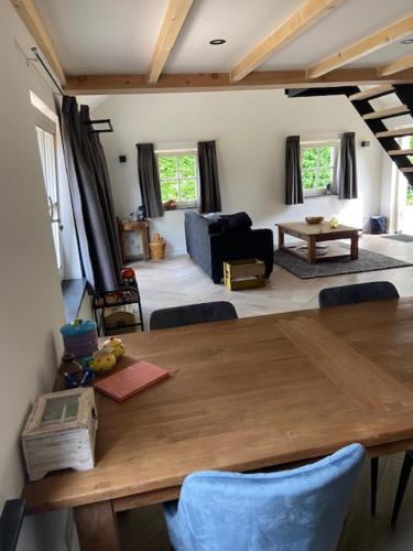 a dining room with a wooden table and a living room at Op den Distelberg in Helvoirt