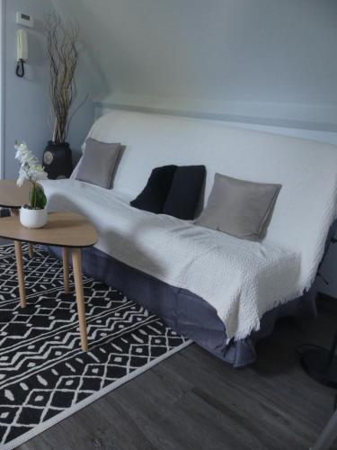 - un lit blanc avec des oreillers et une table dans la chambre dans l'établissement Le bon plan entre Caen et la mer ** Draps et ménage inclus !**, à Giberville