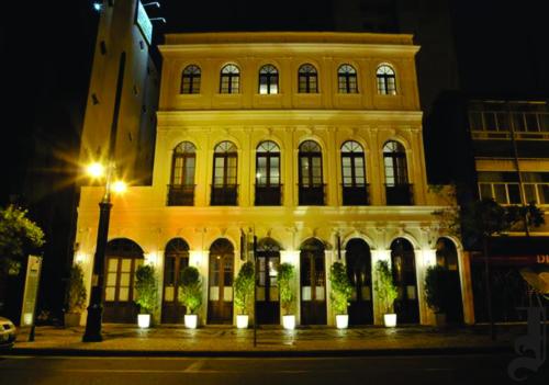 a large yellow building at night with a street light at Johnscher by San Juan in Curitiba