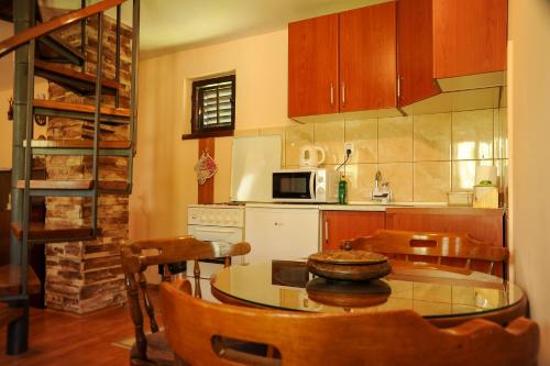 eine Küche mit einem Tisch, Stühlen und einer Mikrowelle in der Unterkunft LOVCEN4ME in Cetinje