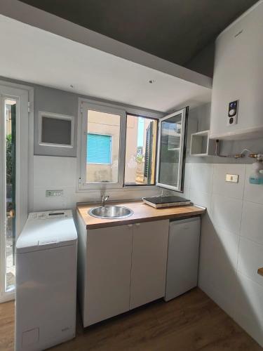a small kitchen with a sink and two windows at La Casina Small Loft in Versilia in Marina di Carrara