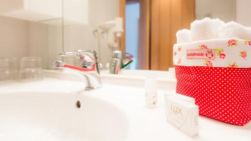 - un lavabo dans la salle de bains avec porte-serviettes rouge et blanc dans l'établissement Gasthof Menüwirt, à Sankt Kanzian