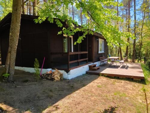 a cabin in the woods with a wooden porch and a picnic table at Pensjonat Sawica in Szczytno