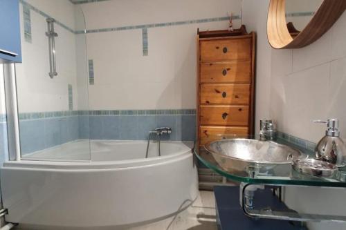 een badkamer met een groot bad en een wastafel bij La Chaumière de Mano in Berville-sur-Mer
