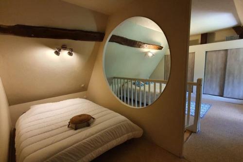 een slaapkamer met een bed met een ronde spiegel bij La Chaumière de Mano in Berville-sur-Mer