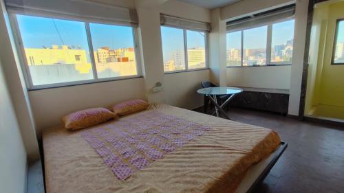 1 dormitorio con 1 cama en una habitación con ventanas en Blue Lagoon en Pune