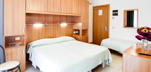 una camera d'albergo con due letti, una scrivania e armadi di Hotel Colorado a Lido di Jesolo