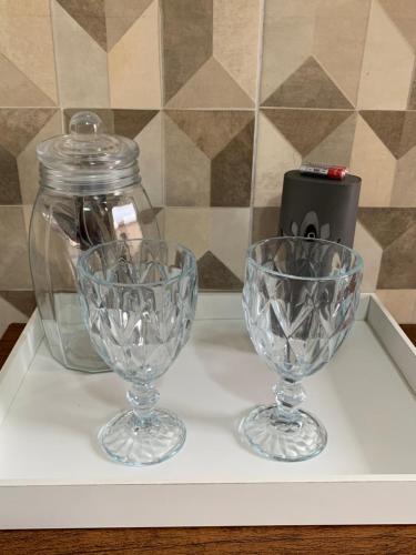 two wine glasses and a jar on a shelf at Suíte 101- Espaço Praia Aptos in Angra dos Reis