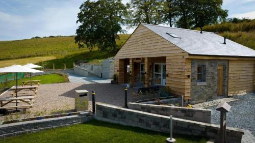 a small wooden cabin with a table and an umbrella at Forestview Cabin No 1 - cosy cabin stay in Ballynahinch