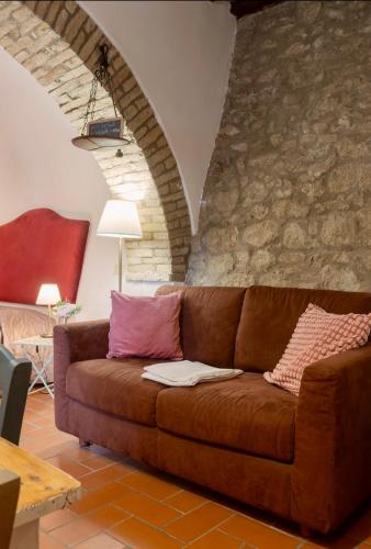 a brown couch in a living room with a stone wall at Le Fonti di San Gimignano in San Gimignano