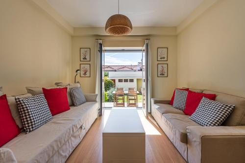a living room with two couches and red pillows at GuestReady - City & Beach Garden Home in Porto