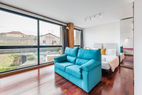 a living room with a blue couch and a bed at GuestReady - Zarco Studio in Leça da Palmeira