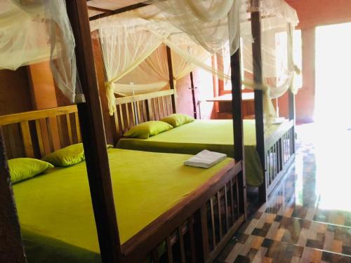 two bunk beds in a room with green sheets at Belihuloya Terico Resort in Balangoda