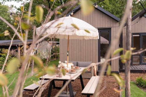 a picnic table with an umbrella in a yard at WØUD Tiny House in Epe