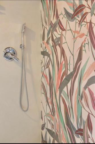 a shower nozzle in a bathroom with a floral shower curtain at Le Fonti di San Gimignano in San Gimignano