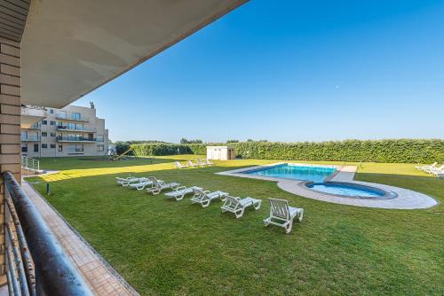a group of lawn chairs and a swimming pool at GuestReady - Madalena Beach Pool & Tennis in Vila Nova de Gaia