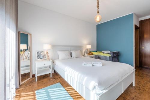 a bedroom with a white bed and a blue wall at GuestReady - Madalena Beach Pool & Tennis in Vila Nova de Gaia