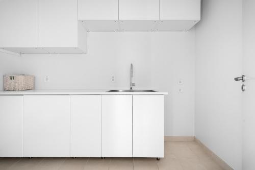 eine Küche mit weißen Schränken und einem Waschbecken in der Unterkunft Amazing View - 5 bedrooms - new house - modern and exclusive in Bergen