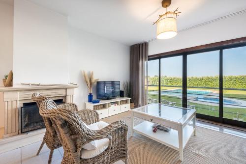 a living room with chairs and a fireplace and a tv at GuestReady - Madalena Beach Pool & Tennis in Vila Nova de Gaia
