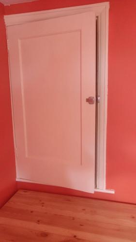 a white door in a red room with a wooden floor at L'Auberge close Syon Lane Station and Heathrow in London