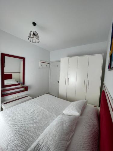a white bedroom with a bed and a mirror at BlueCoast Apartment Vlore in Vlorë