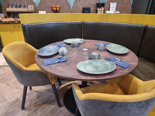 una mesa de madera con platos y servilletas. en ibis Styles Dijon Sud Domaine De Beauregard 21600 Longvic en Dijon