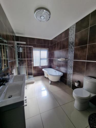 a bathroom with a tub and a toilet and a sink at The Executive 5 BnB in Manzini