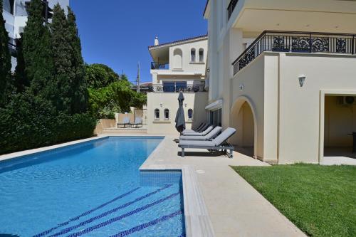 einen Pool mit Liegestühlen neben einem Haus in der Unterkunft Villa Domus Riviera in Athen