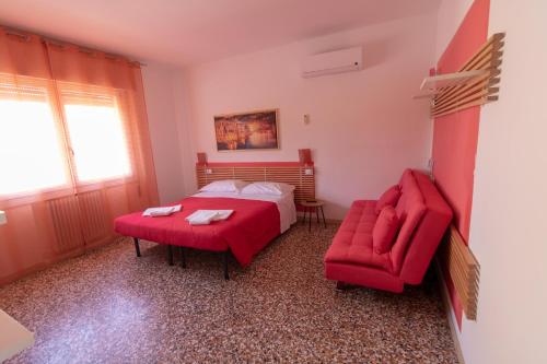 a bedroom with a red bed and a red chair at GreenColors Hotel in Campalto