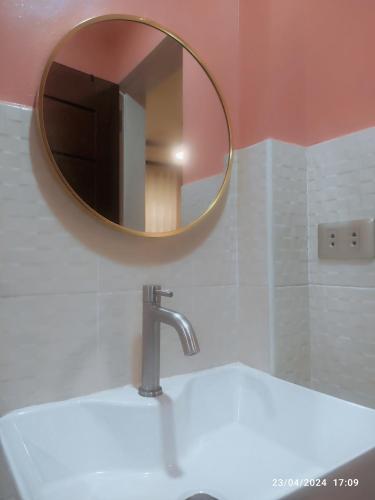 a bathroom sink with a round mirror above it at Casita de Reina Staycation House - A cozy 1-Bedroom condo-style house in Locsin